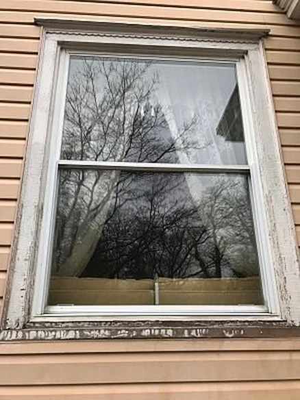 Outdated white window on tan siding. 