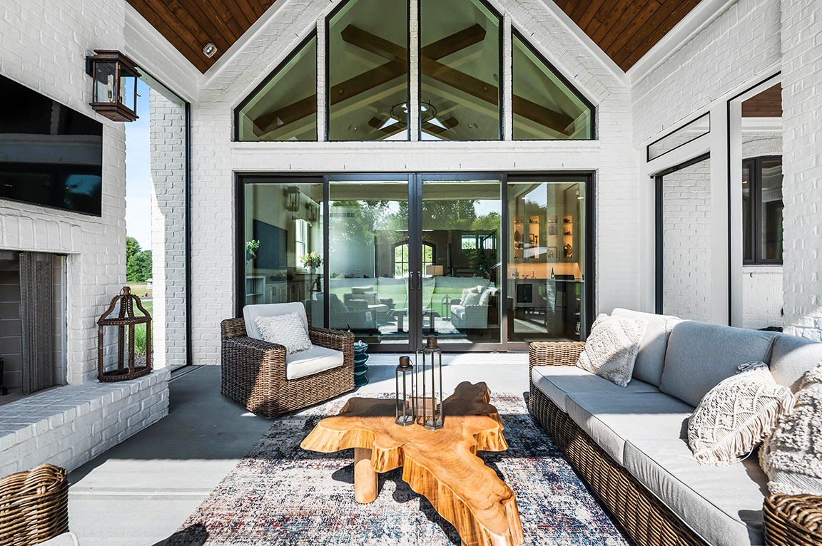 Covered outdoor patio with wicker furniture, wood coffee table, and sliding glass doors