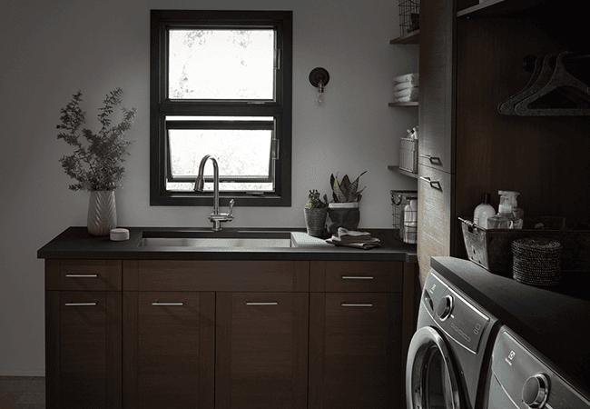 A laundry room with two stacked black awning windows above the sink.