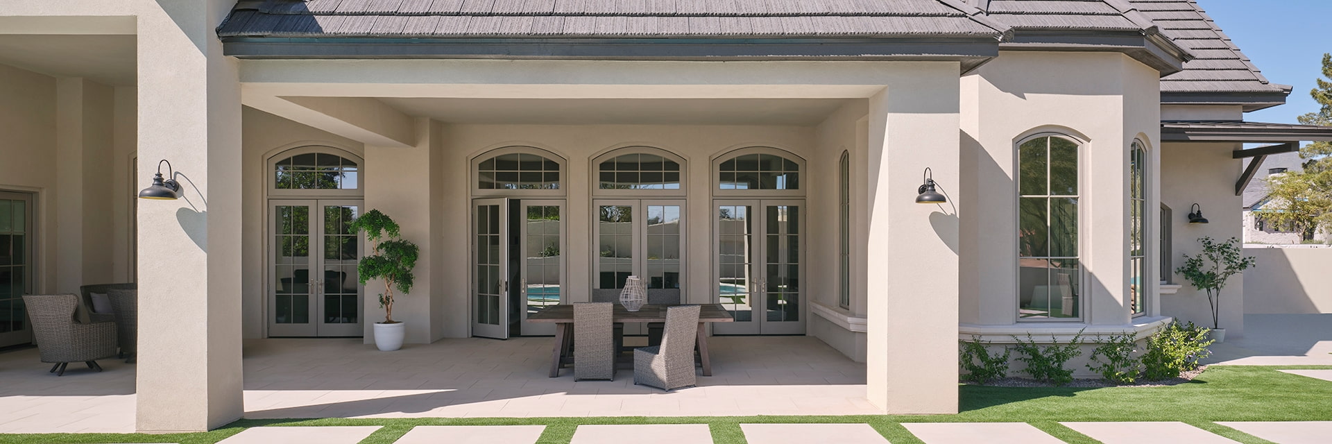Three sets of french doors that are reflecting the outdoors on the glass behind an outdoor patio.