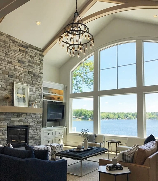 Grand room view of a newly built Michigan home highlighting arched windows with a beautiful lakeside view.