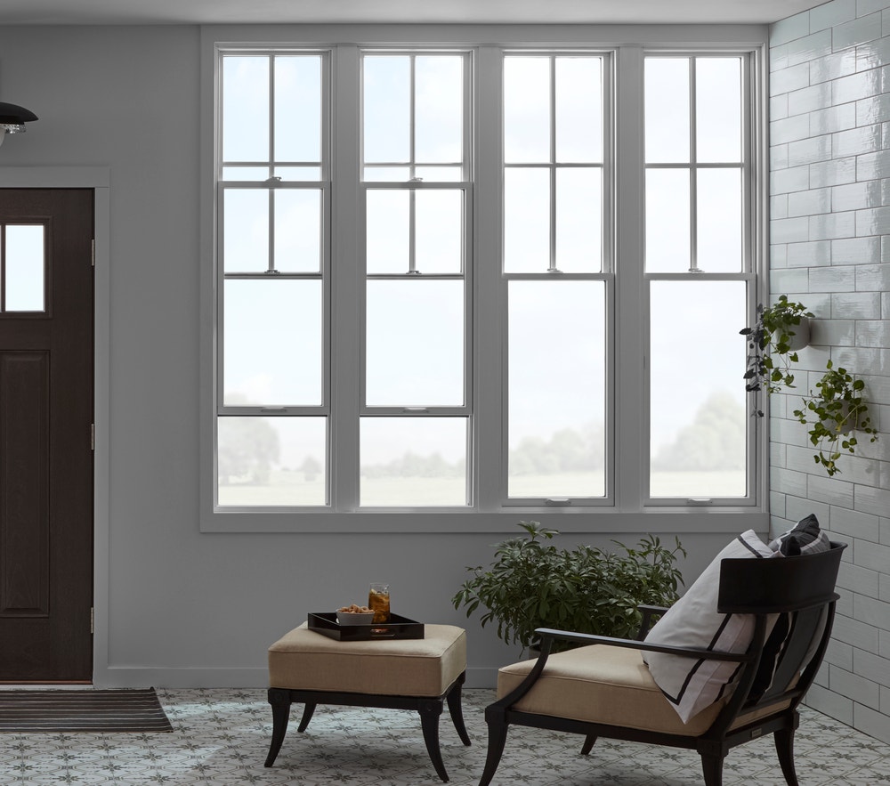 Four tall single-hung windows with chaise lounge chair underneath