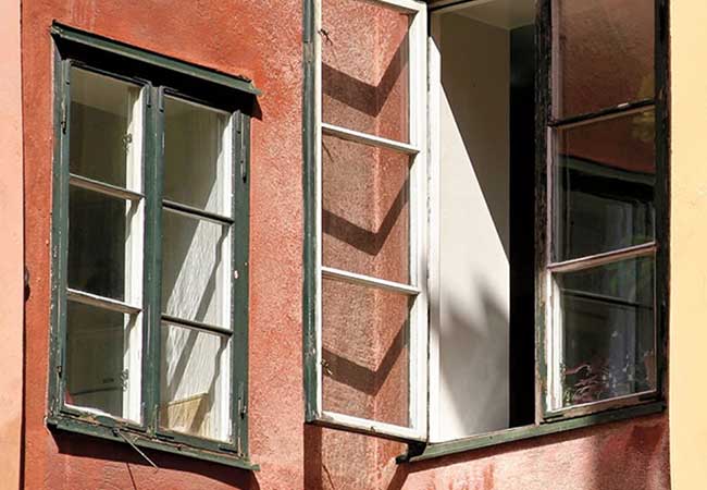Exterior view of old green casement windows on a red building.