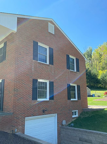 new white windows on a brick home with a blue sky overhead