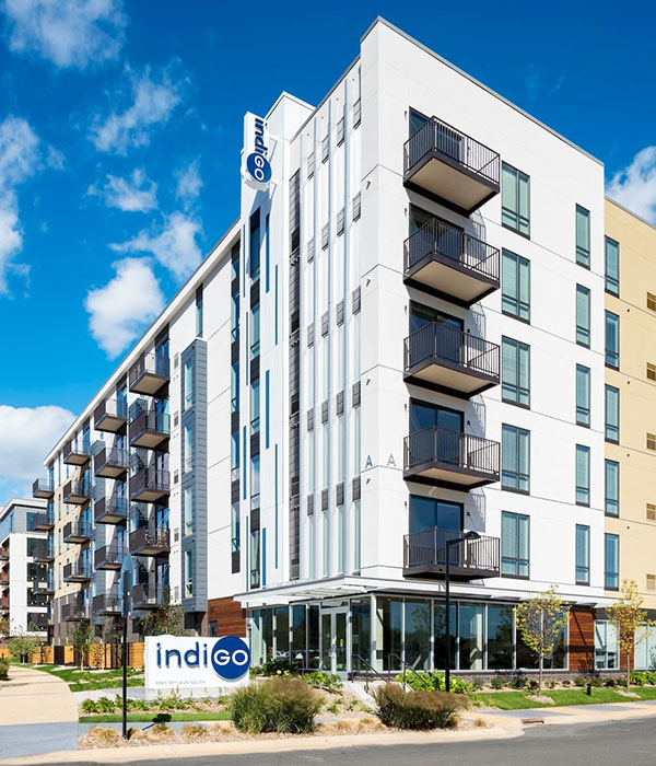 Alt Text: Curbside view of newly constructed Bloomington apartment building with modern sound-resistant windows. 