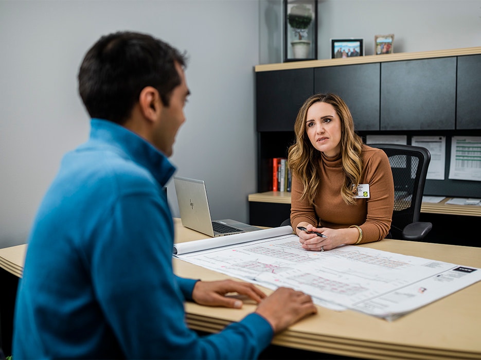 two pella employees discussing a drawing for a new building