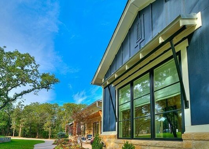 3 black-trimmed casement windows on a blue and brick home