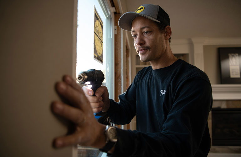 A Pella installer is sealing a window after installation to prevent air leaks.
