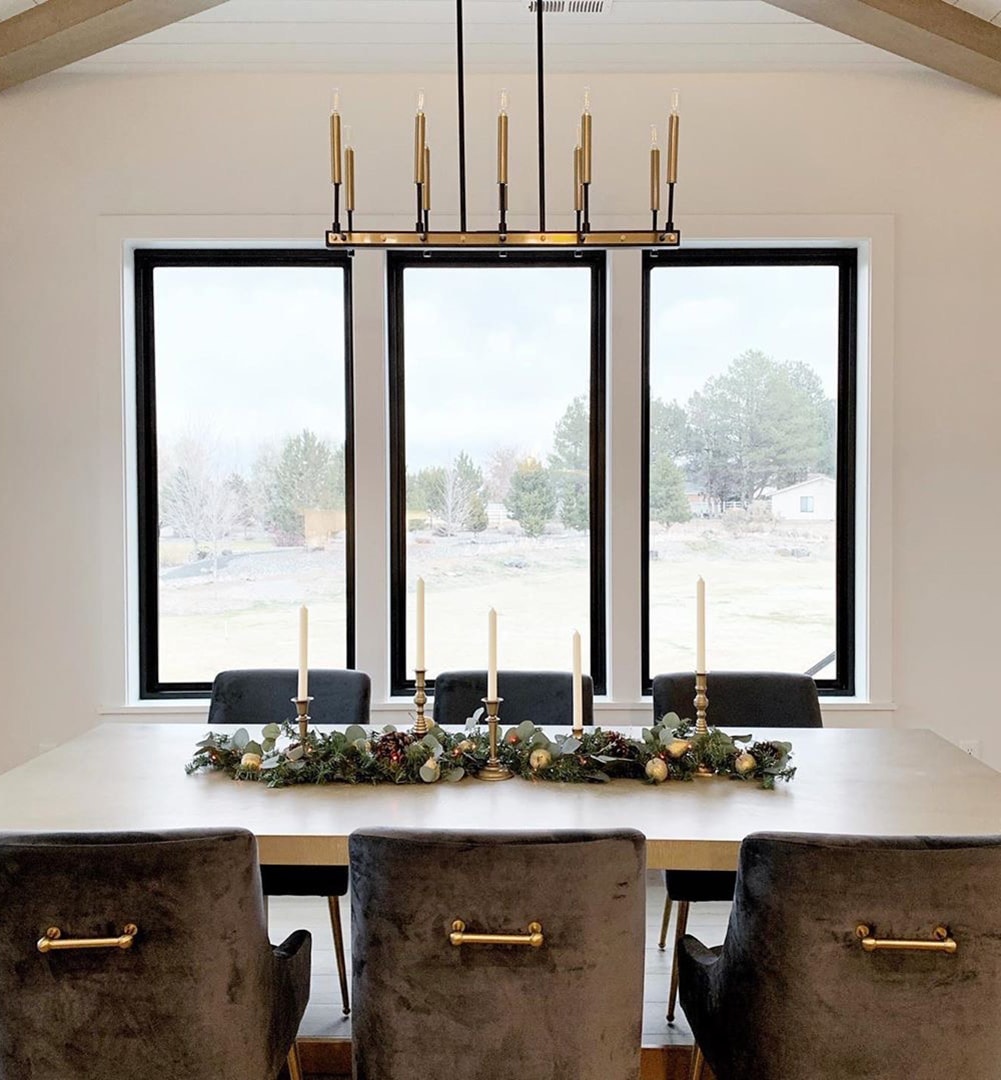 Three black picture windows behind table in modern dining room.