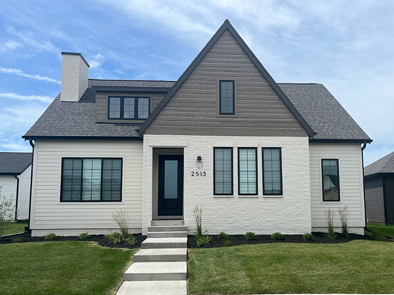 the exterior of a white brick home with gray accent siding and casement windows along the front walls