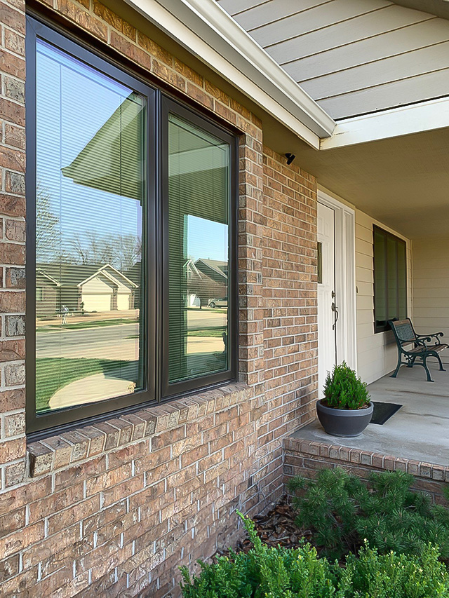 A close-up view of modern casement windows on a brick exterior home, showcasing the entrance and landscaping.