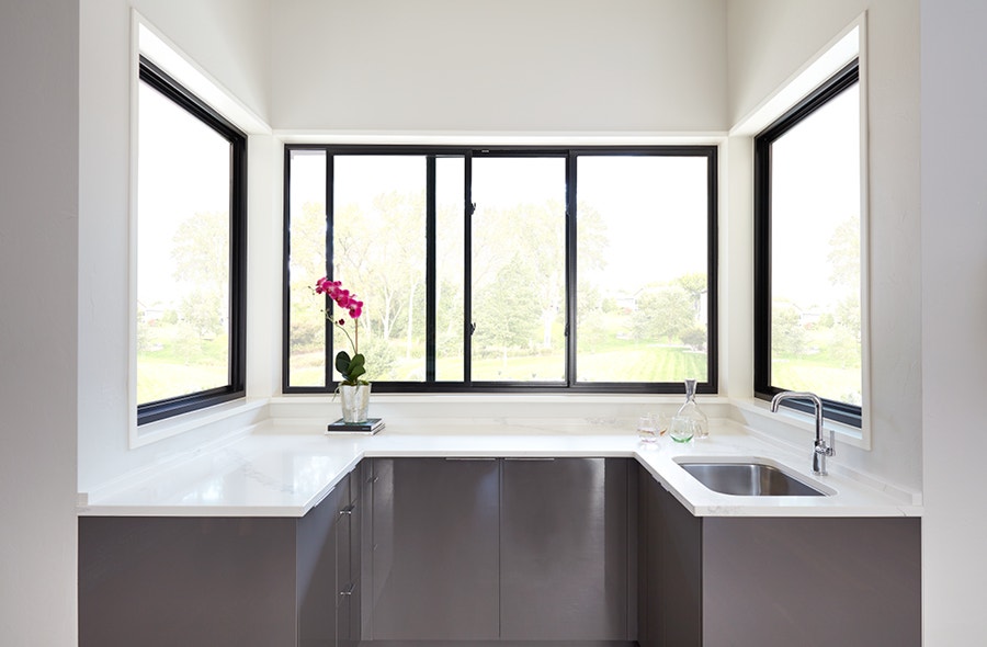 Nook with integrated sink in marble countertop with black pass-through windows above it