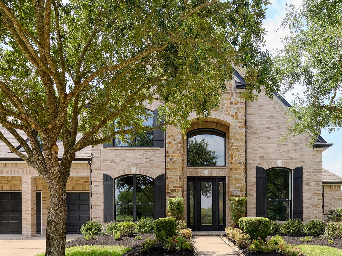 Stone home exterior with arched windows and black window frames.