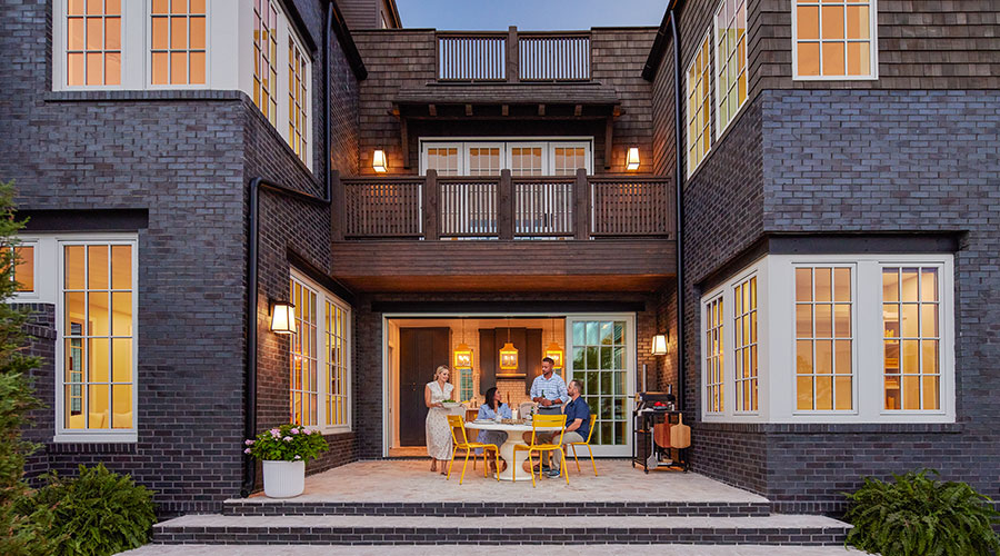 outdoor patio placed between the two wings of a large brick home