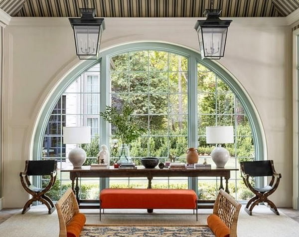 a three-wide set of arched windows form a backdrop behind a contemporary dining-room table.