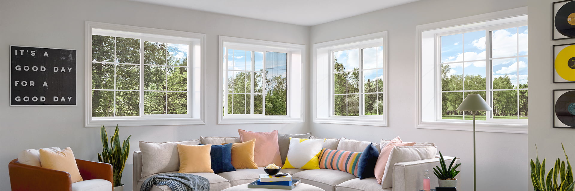 a white corner sofa with large colorful pillows sits underneath four sets of sliding windows.