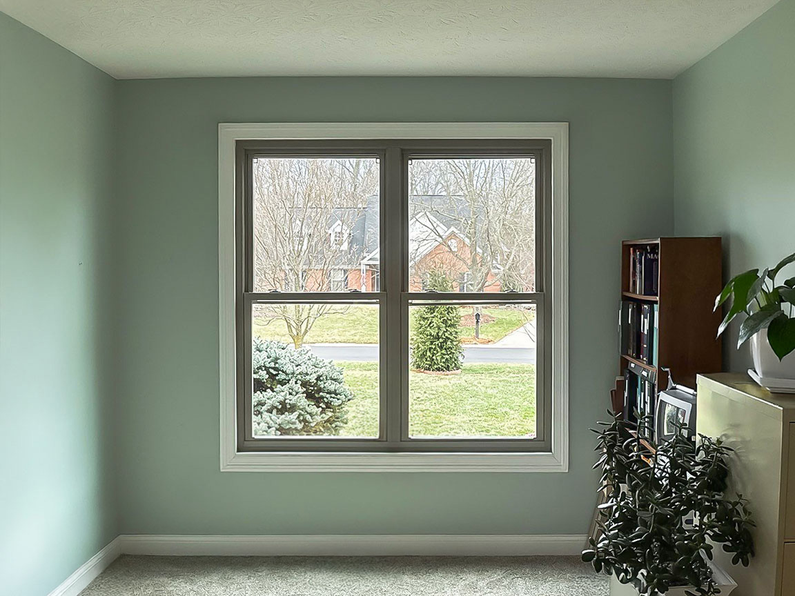 Home office with large window providing natural daylight and yard view.