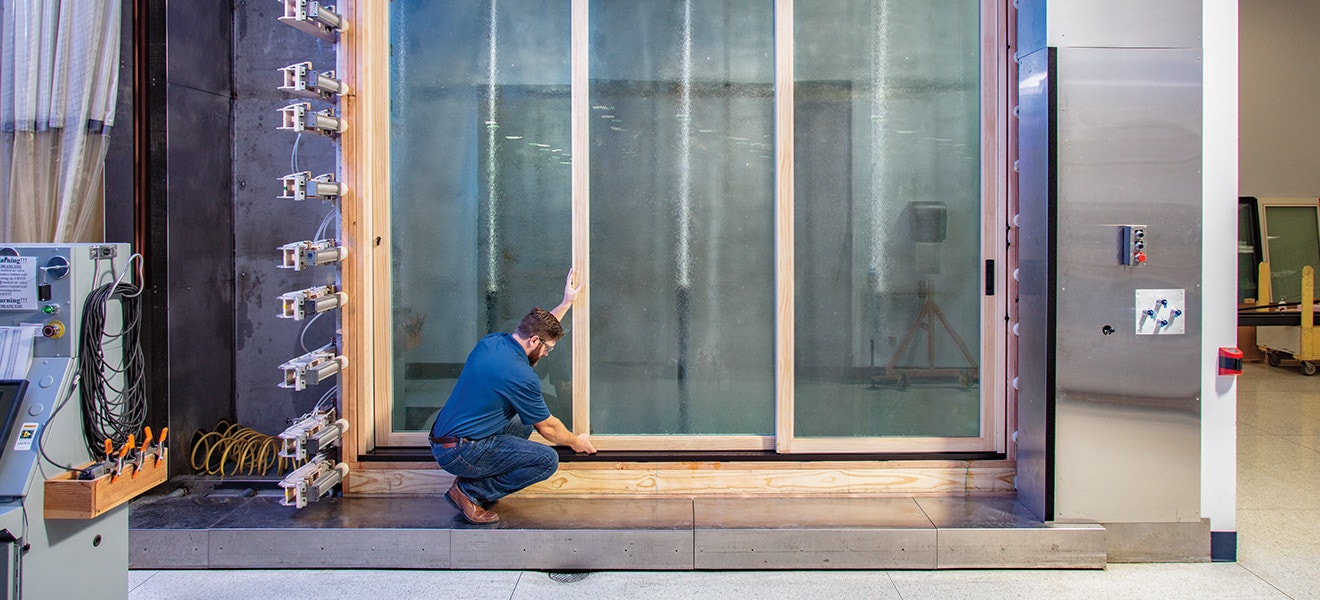 pella employee standing in front of large multi-slide door being tested for weather-resistance