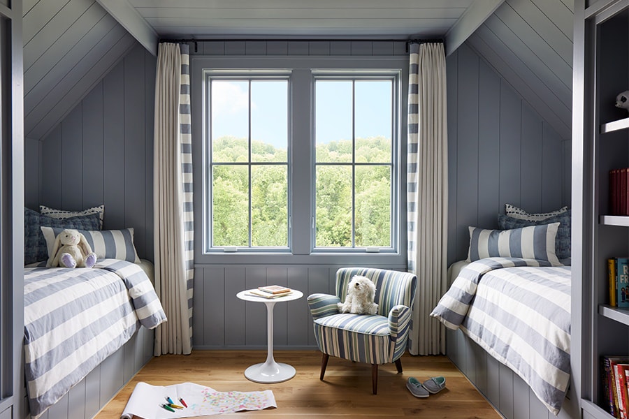 a charming kids bedroom where the bedding and window covers match and two double-hung windows for fresh air.