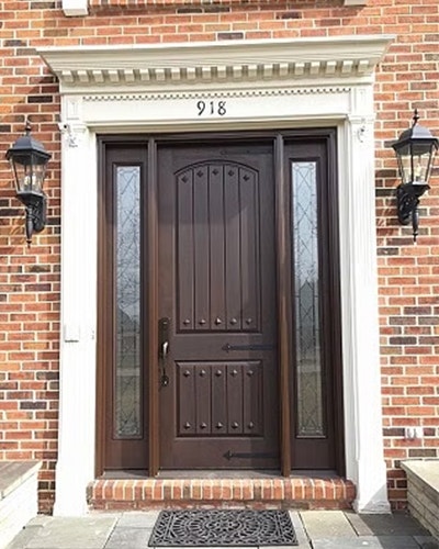 A brick home with an updated fiberglass front door and full light sidelights with decorative glass.