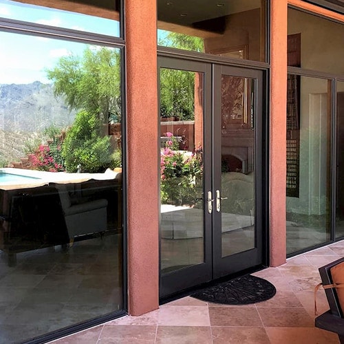 Tucson-area cement patio that leads to a set of wood french doors that open to the interior.