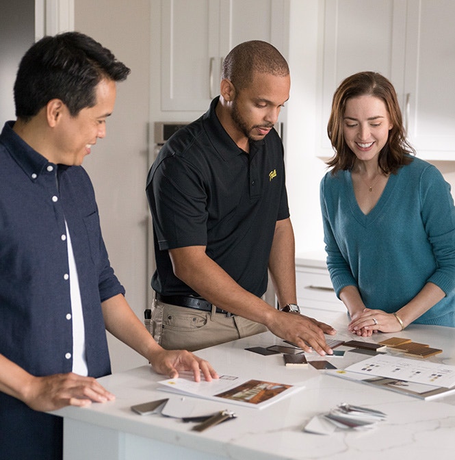 Three people reviewing design materials on a white countertop in a Philadelphia home.