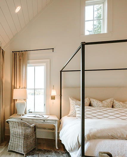 Elegant bedroom featuring a traditional window overlooking the outside from the upstairs. 