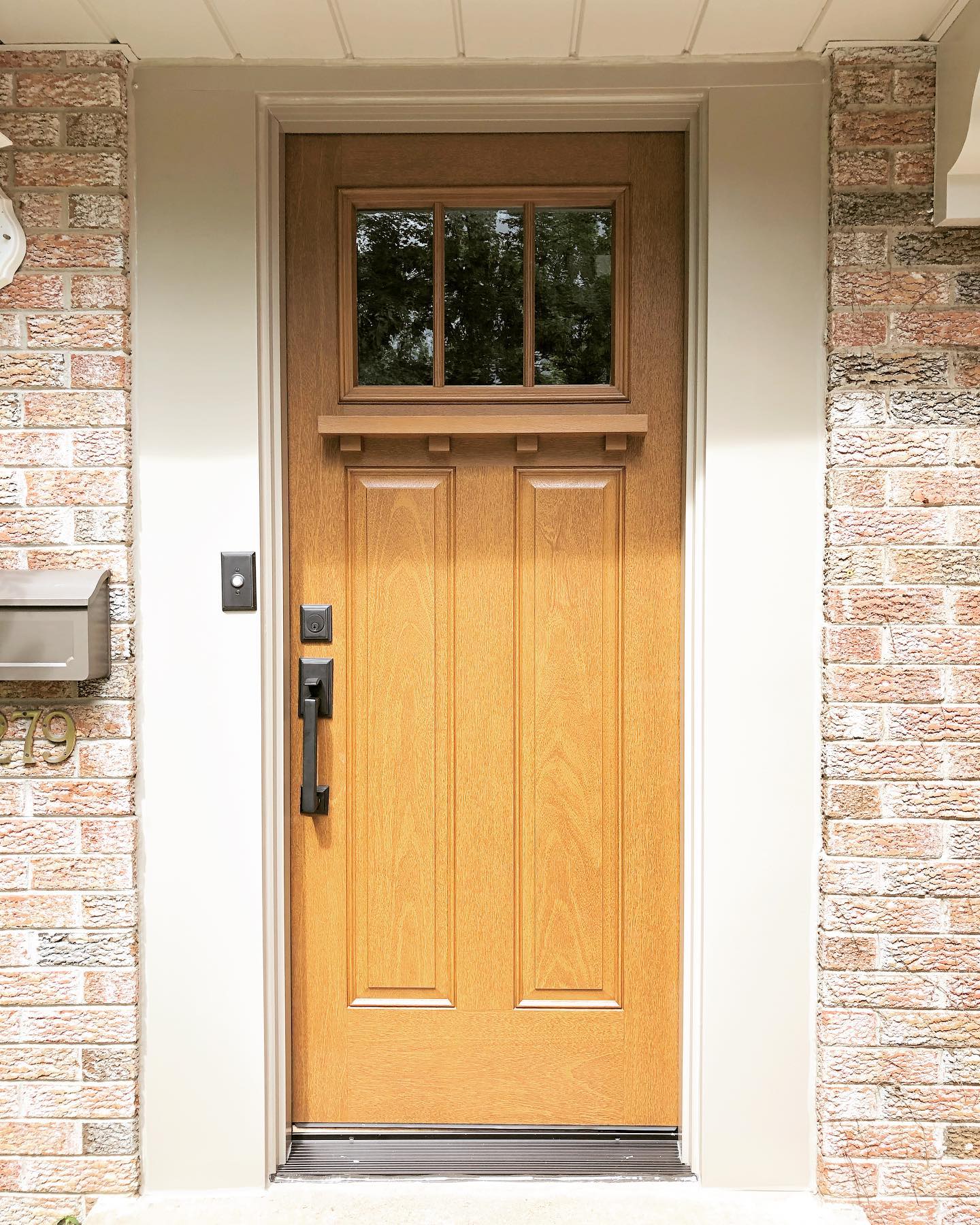Craftsman style front door in fiberglass wood grain on brick house