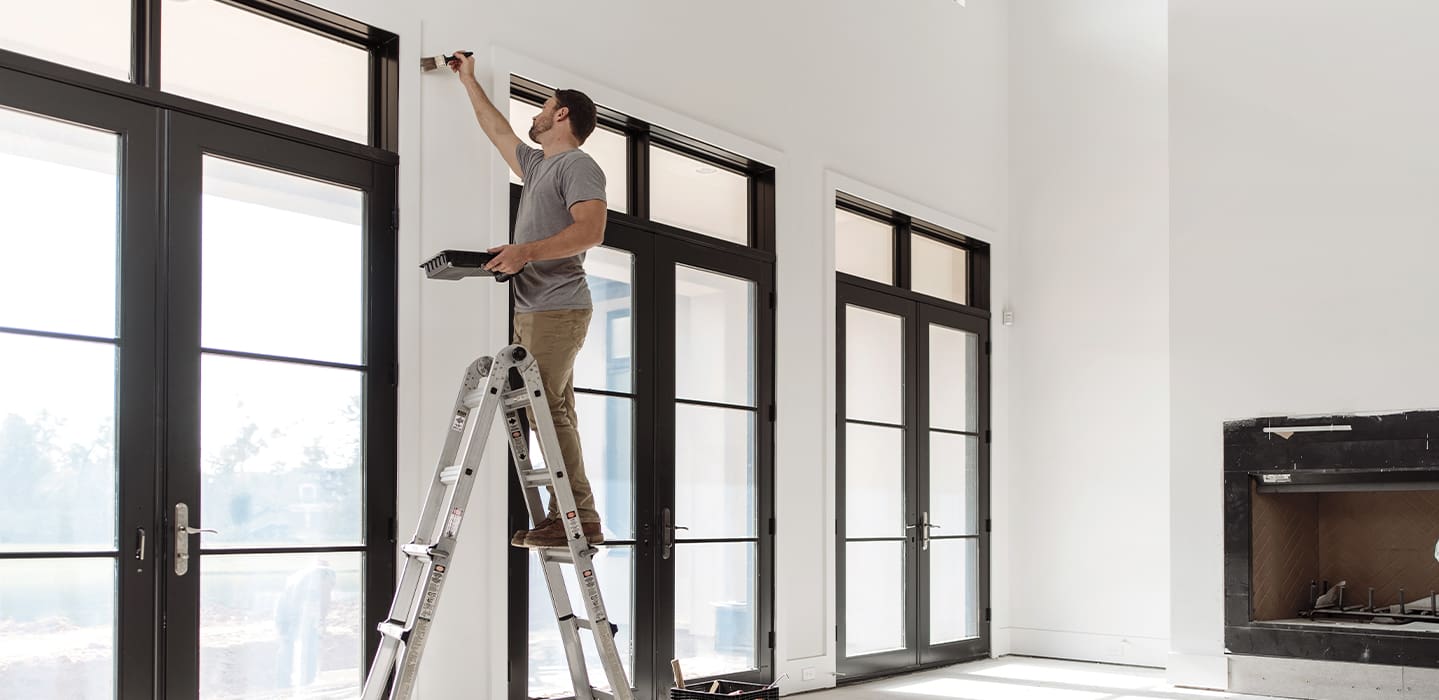 man on a ladder working on hinged patio doors