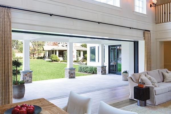 An expansive multi-slide door is fully open, bringing the exterior patio as part of the home