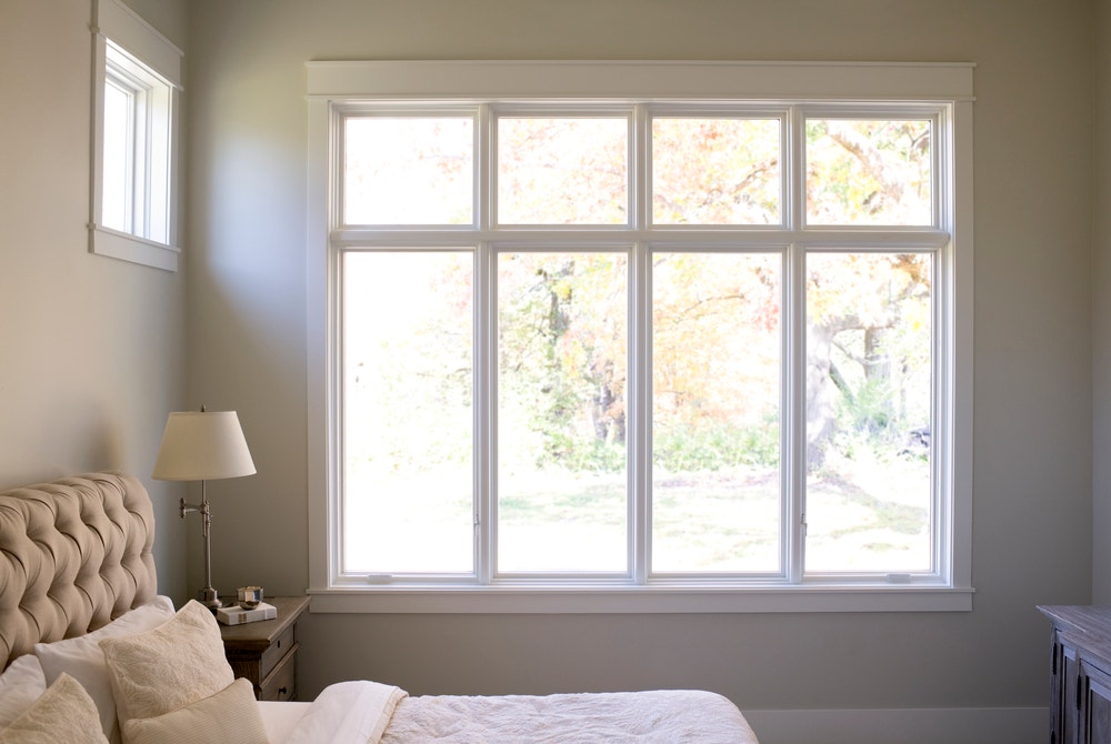 Row of four white windows with white trim in beige bedroom