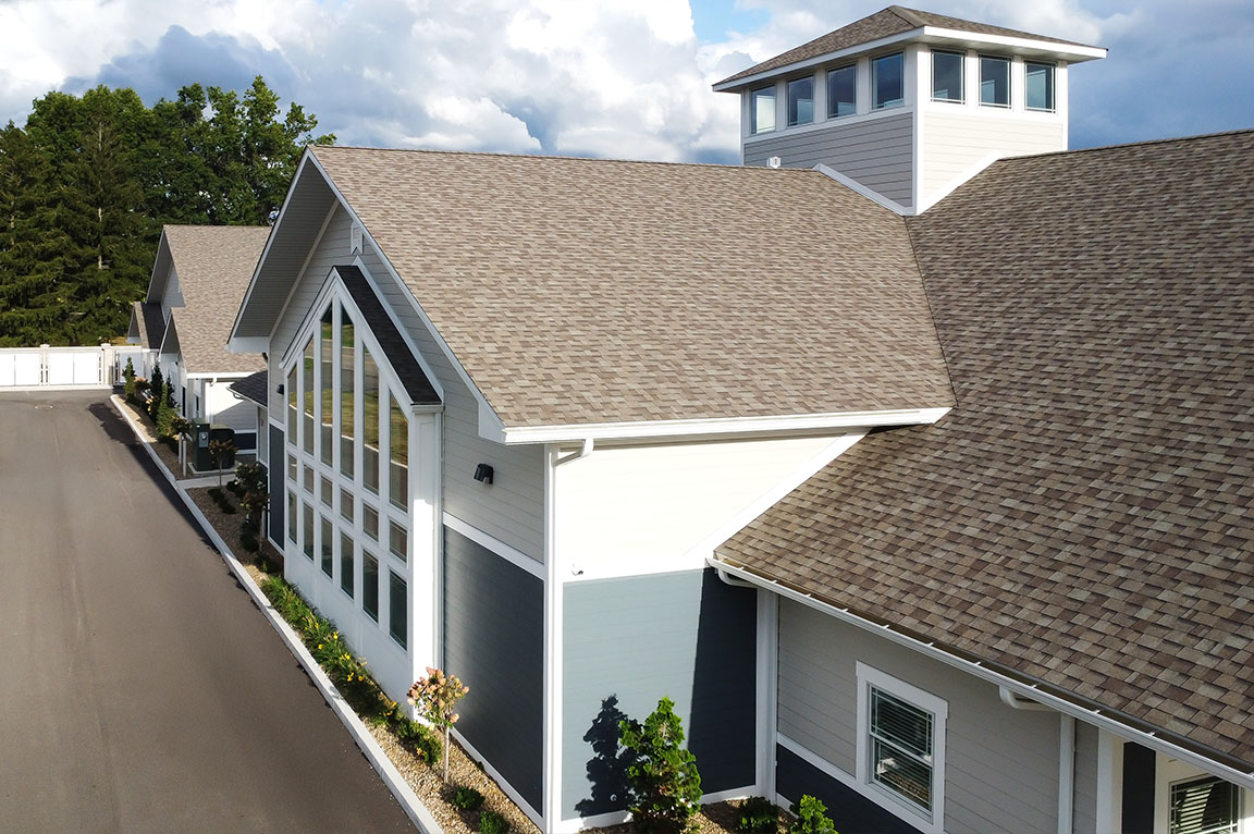 Angled view of a commercial building featuring tall windows and pitched roof.