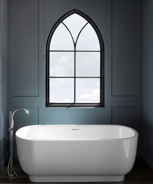 white bathtub in a dark bathroom and a single arched gothic window