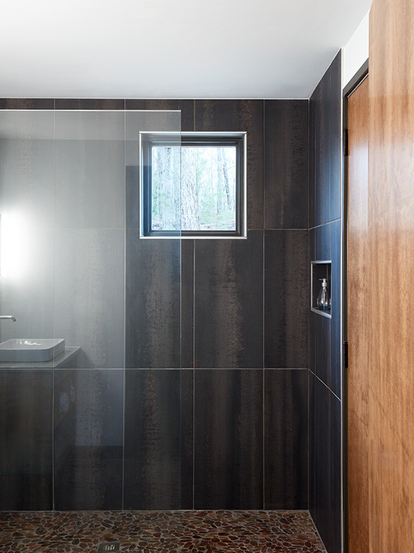 small shower window in a dark-tiled shower