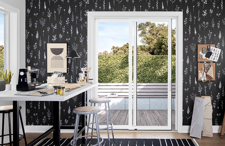Sewing room with black patterned wallpaper and a white sliding door