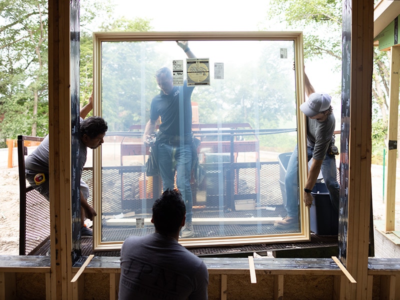 a team of men installing a large picture window into a new home