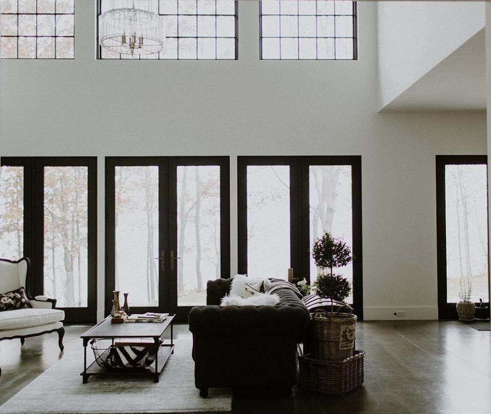 open concept living room with high ceilings and a wall of three black french doors