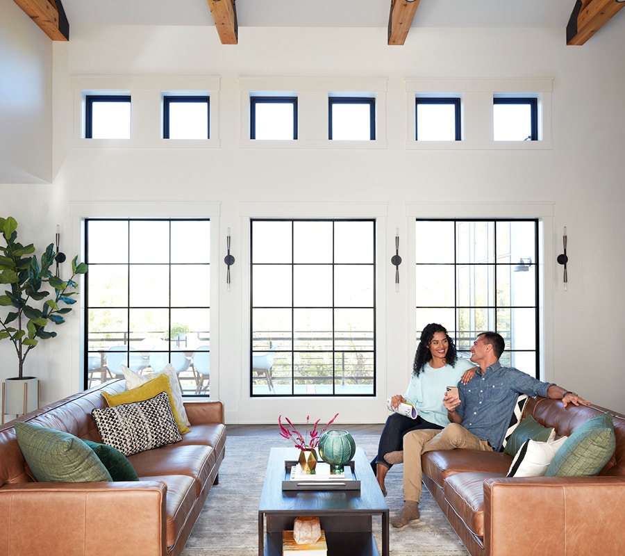 Couple sitting in living room with 3 black picture windows.