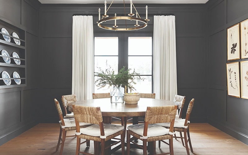 a formal dining room with dark gray walls and a set of french doors on the other side.
