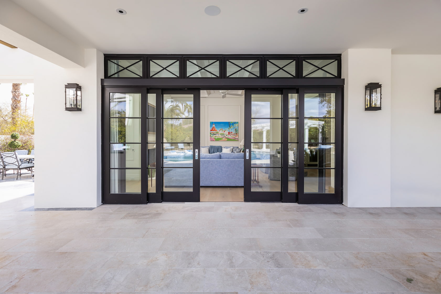 Black multi-slide patio doors with transom windows contrast the white stucco of this home's exterior.