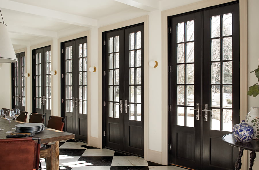 Traditional double black french doors in a large dining room with black and white tile flooring
