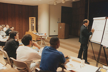 An old image from the 1990s show a group of people learning about continuous improvement together.