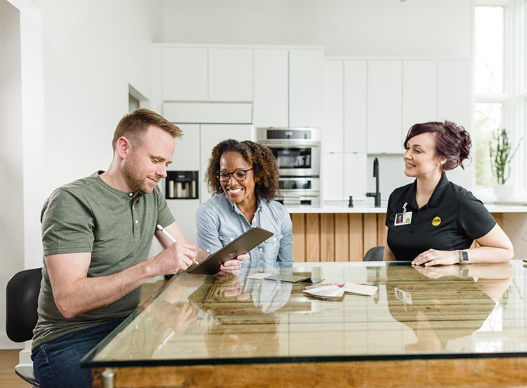 a man and woman signing paperwork during a Pella in-home consultation