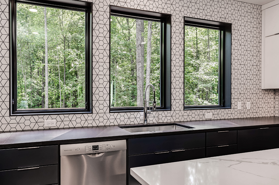 Close up of three black windows above a modern kitchen sink.