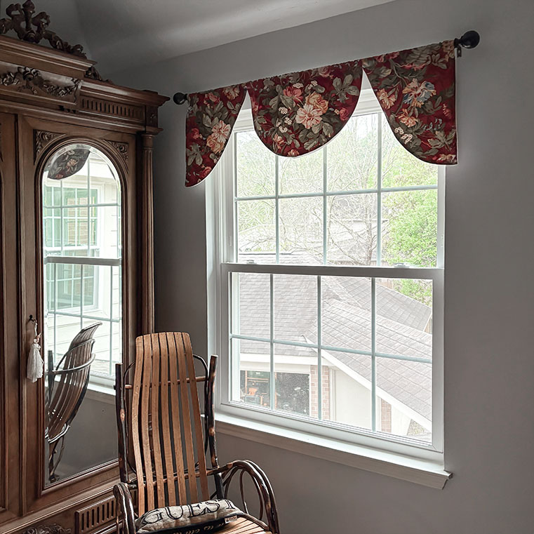 Houston Woodland Home interior with floral valance and wooden chair by a large window.
