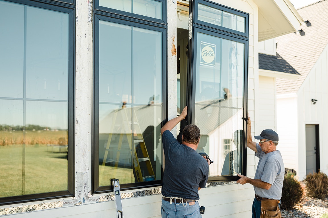A bright room featuring double hung windows with black frames, showcasing a shoe storage unit filled with various footwear.