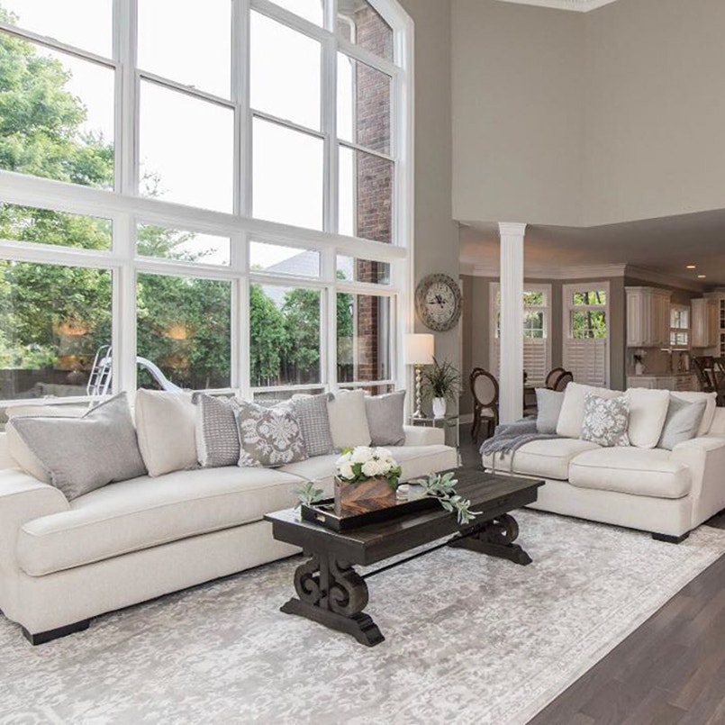 Neutral colored living room with white couches in front of floor-to-ceiling glass windows