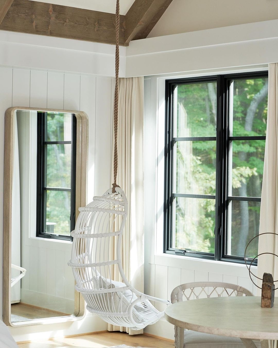 Two black casement windows serve as the backdrop for a white chair hanging from the dining room ceiling.