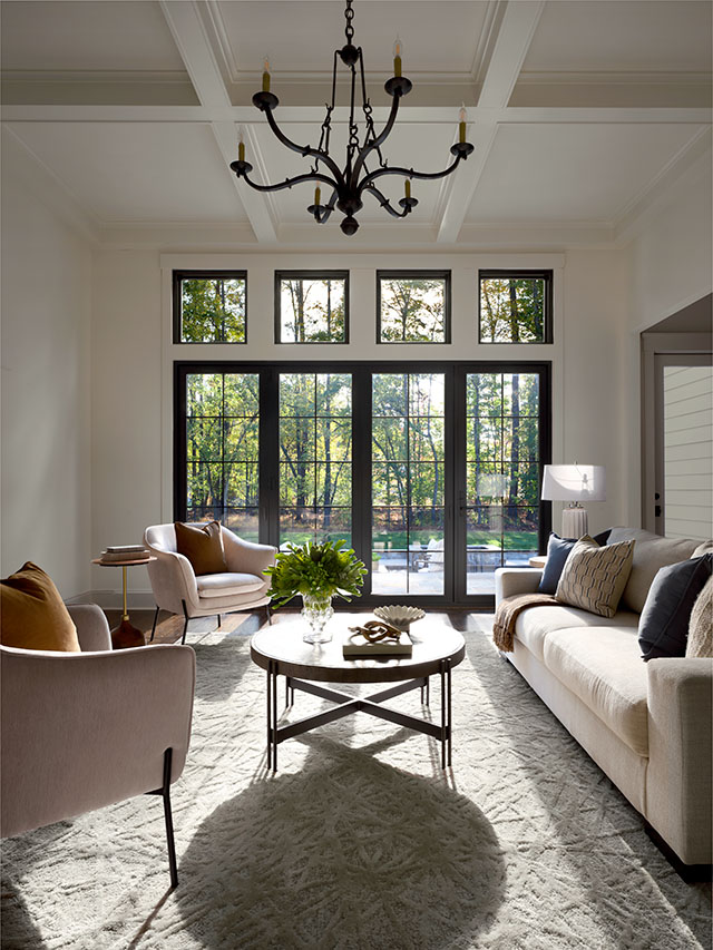 The view of a black four-panel patio door with grilles-between-the-glass on the far side of a long living room.