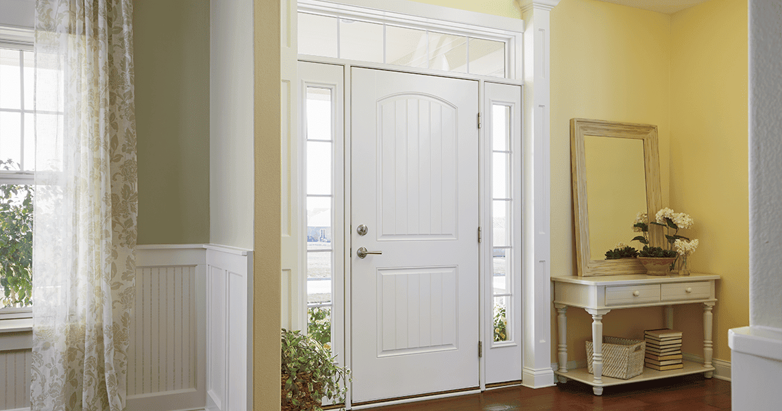 a bright entryway features a white front door with sidelights and transom